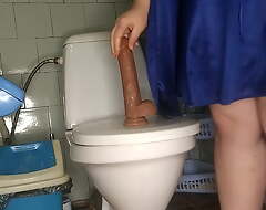 Curvy MILF pissing together with gender her dildo in the toilet